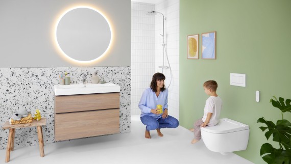 Femme et enfant dans une salle de bains colorée dotée d‘un miroir Geberit Option et d‘un Geberit AquaClean Alba