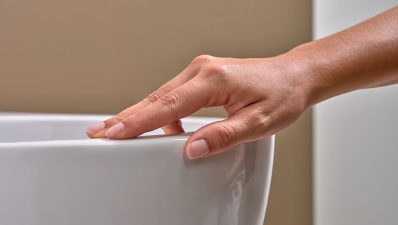 Hand voelt over een wc met een KeraTect® afwerking Hand voelt over een wc met een KeraTect® afwerking
