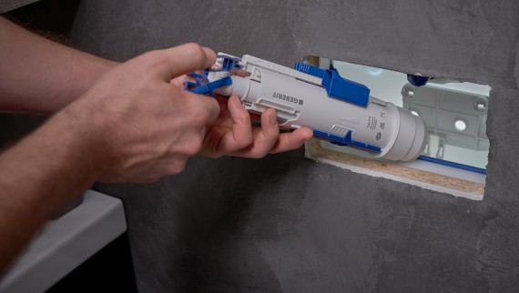 Homme installant une cloche Geberit dans un réservoir de chasse à encastrer (© Ben Huggler). Homme installant une cloche Geberit dans un réservoir de chasse à encastrer (© Ben Huggler).