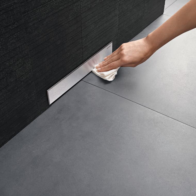 Hand reinigt het deksel van een Geberit wandafvoer Hand reinigt het deksel van een Geberit wandafvoer